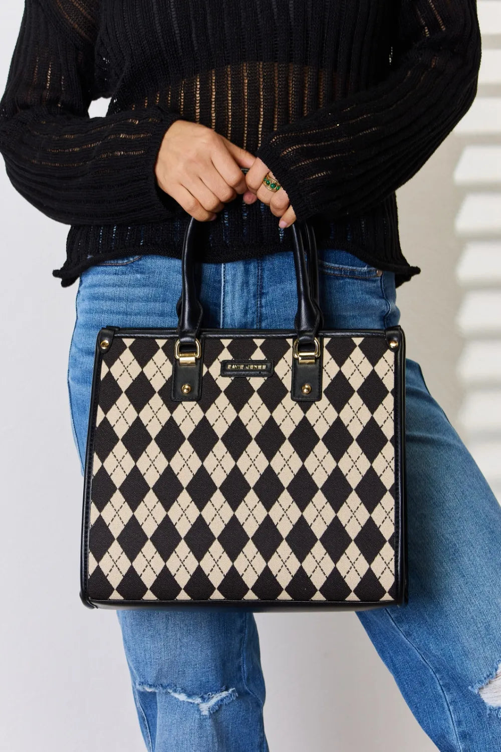Person holding a black and white checkered handbag with a blurred background