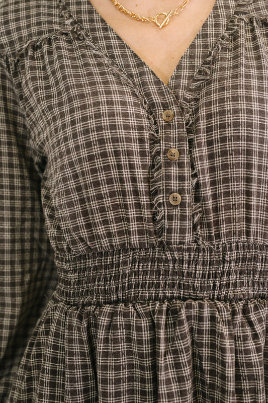 Plaid dress with button details and a gold necklace.