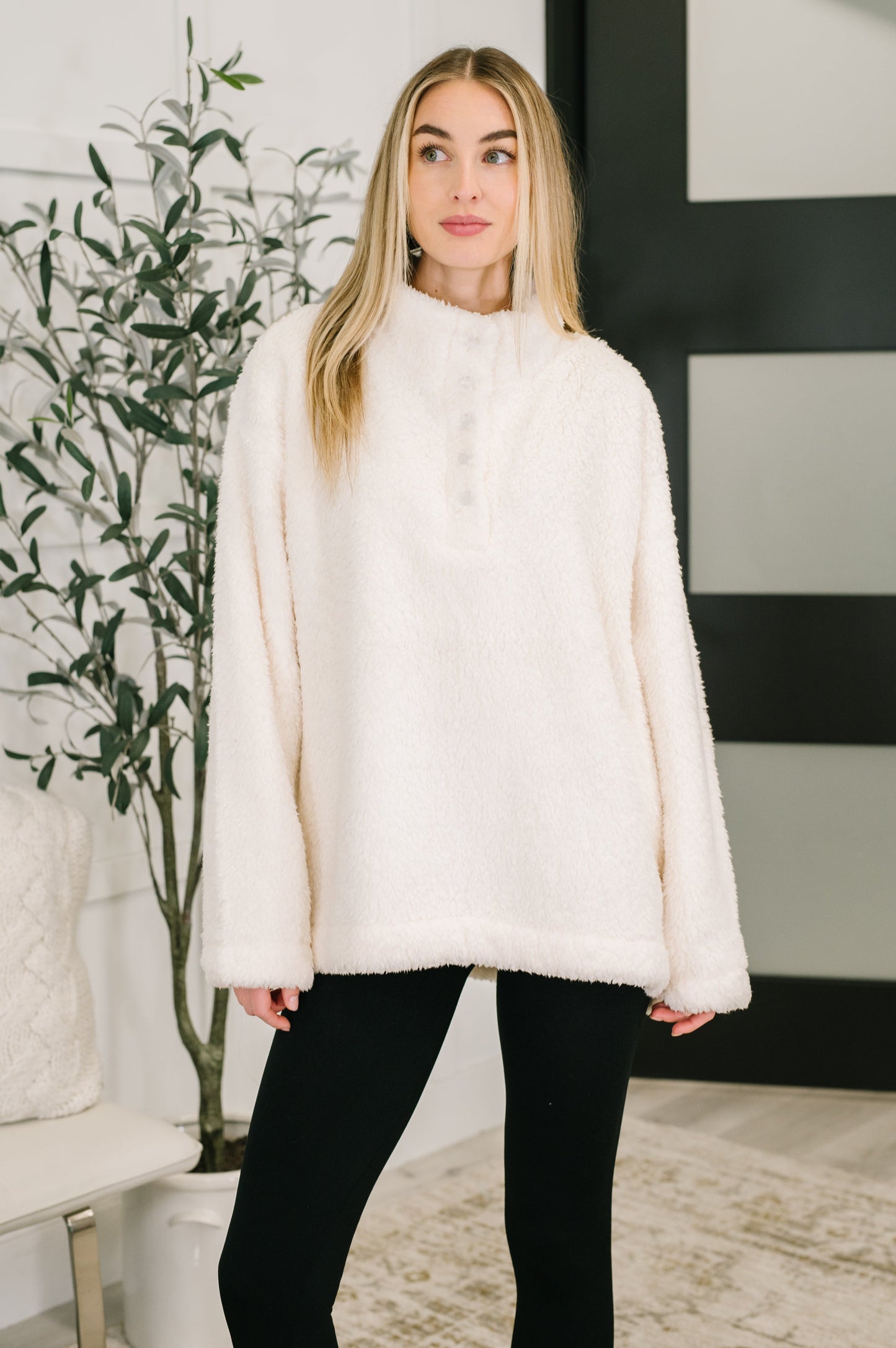Woman wearing a white fur pullover with quarter snap  buttons in an indoor setting