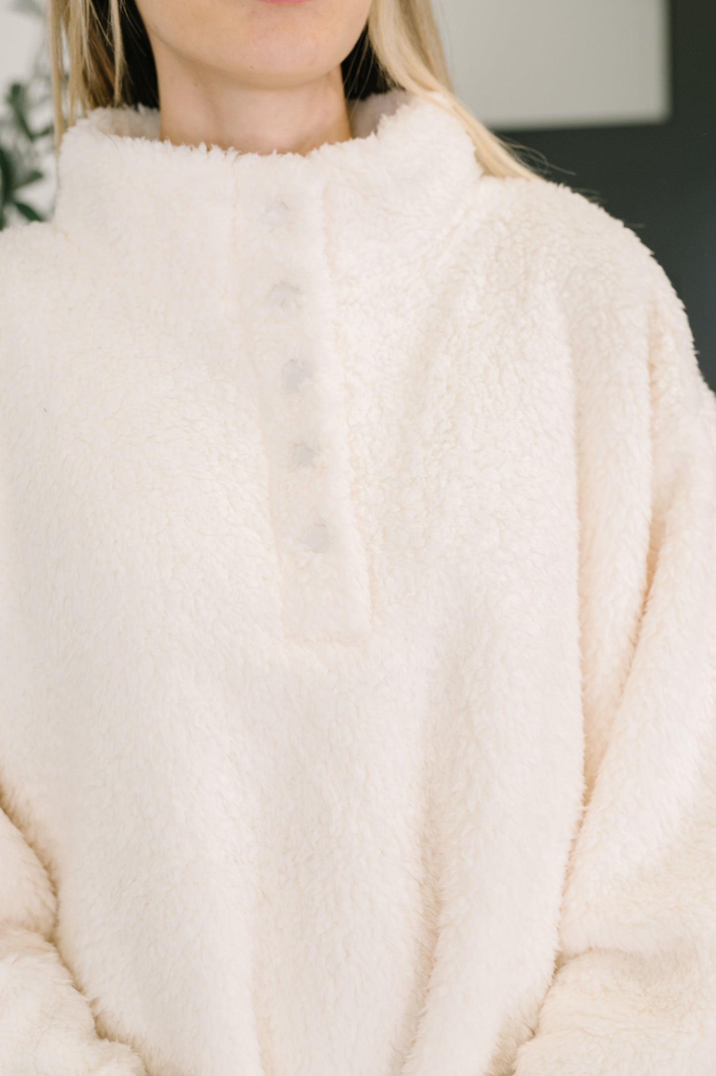 Close-up of a person wearing a white-colored fluffy jacket with quarter length snap buttons