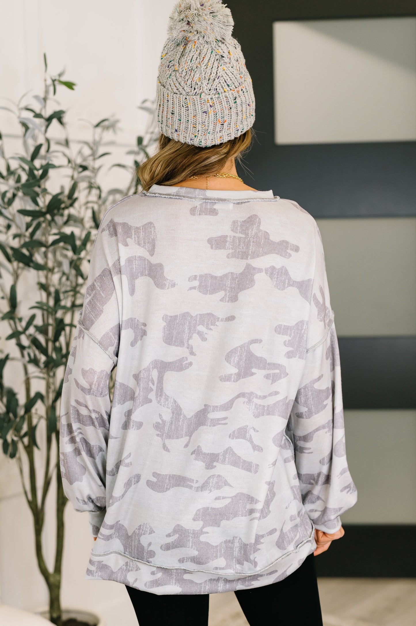 Person wearing a light gray camouflage sweatshirt and a matching beanie indoors.