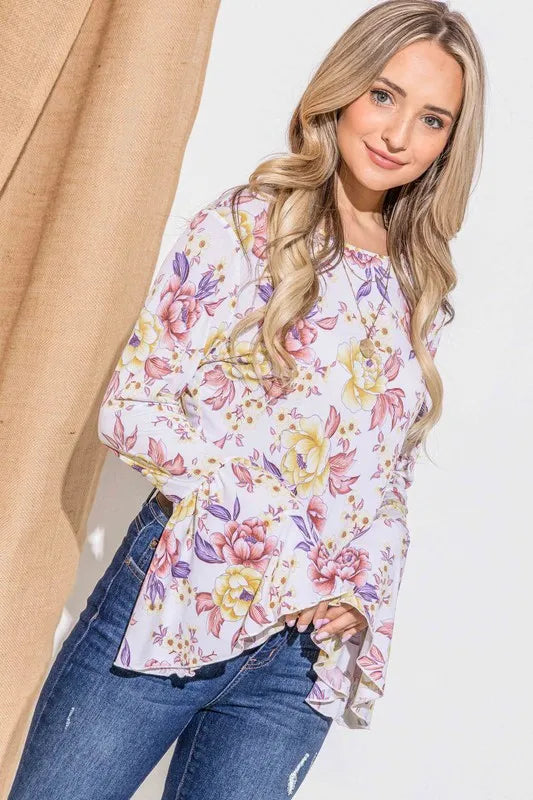 Woman wearing a floral blouse and jeans against a neutral background